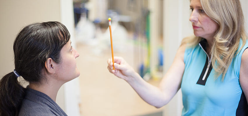 Woman having her eye response tested by staff member